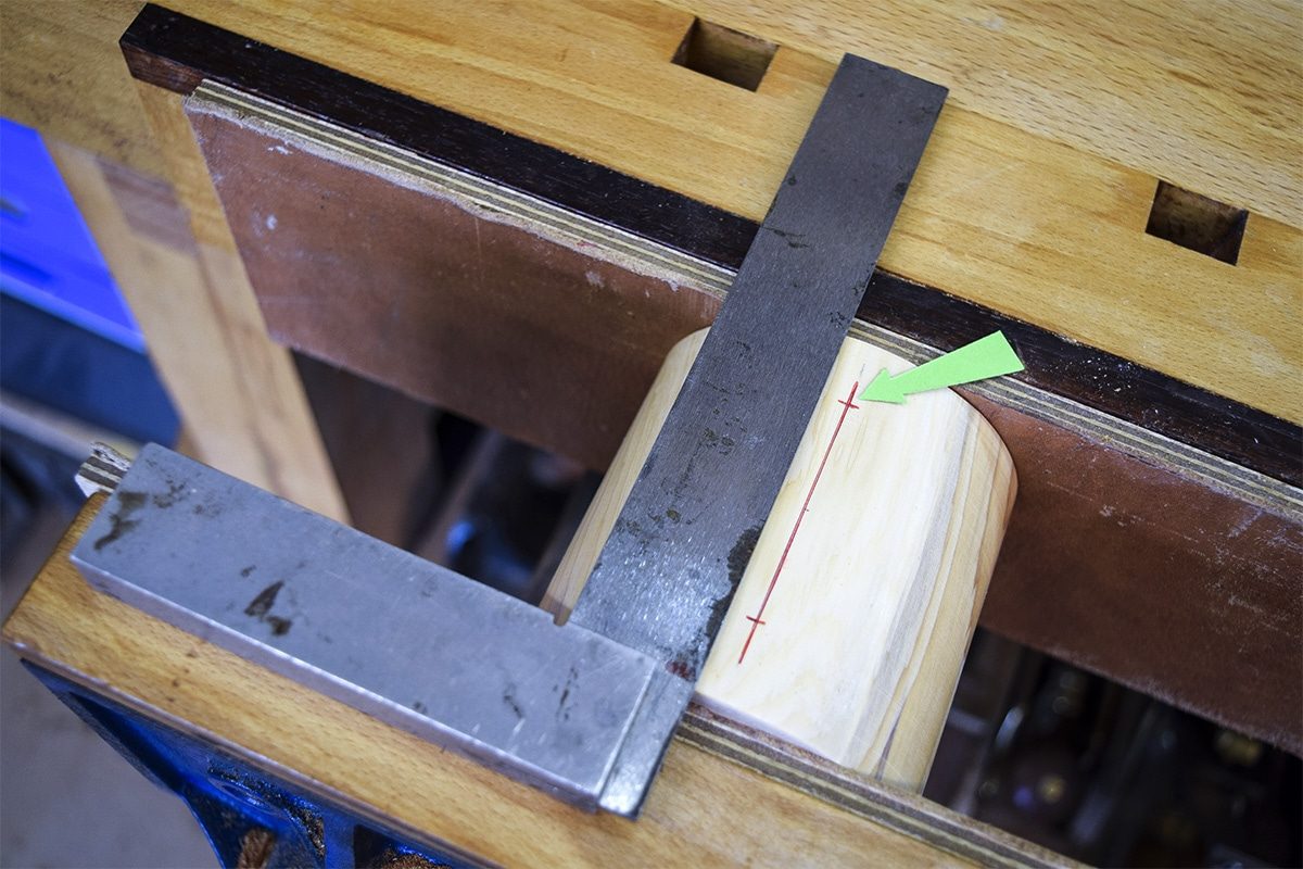 Section of Yew clamped into workbench with marked out lines for screw holes.
