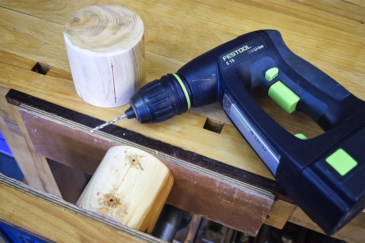 Turned Yew rounds with hold for screws drill out with drill on workbench.