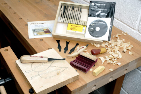 Flexcut carving tool set on workbench with wood held in vice.