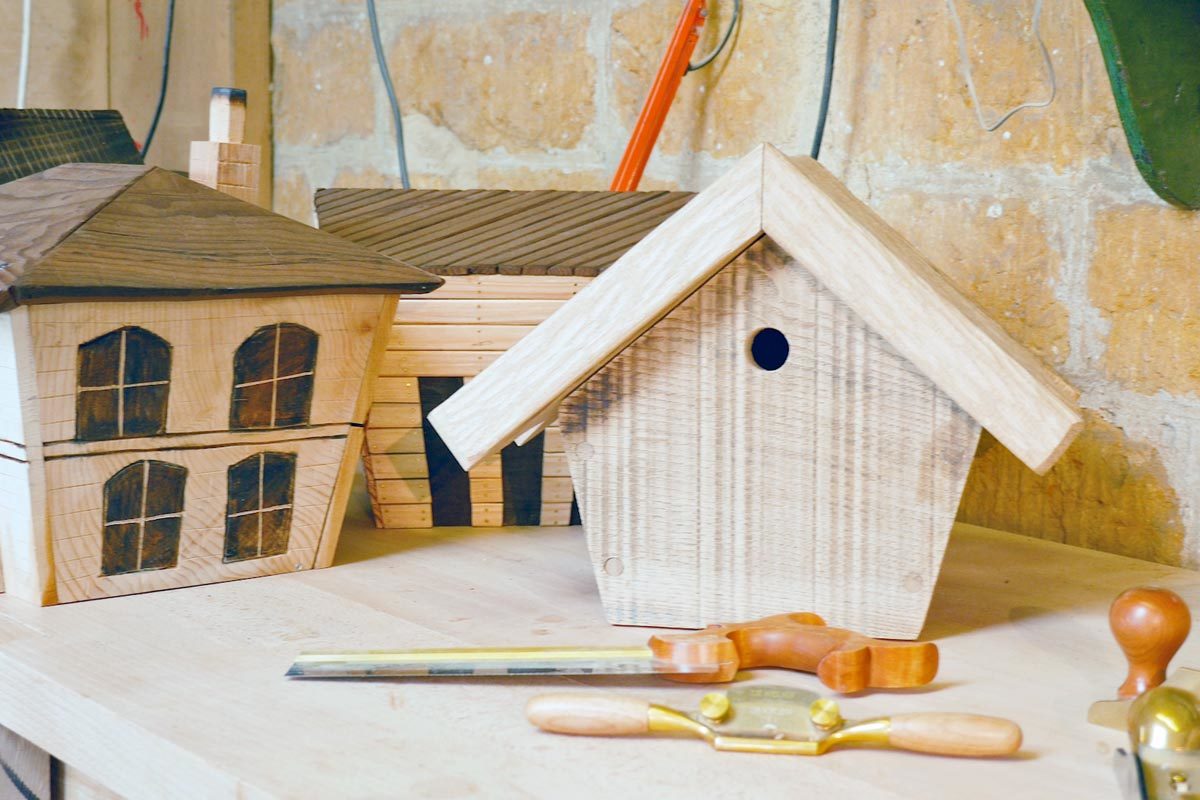 Hand tools in front of three wooden birdboxes