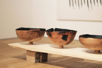 three large turned vessels on a bench in exhibition