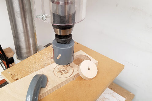 Using a hole saw in a pillar drill to cut out the wheels